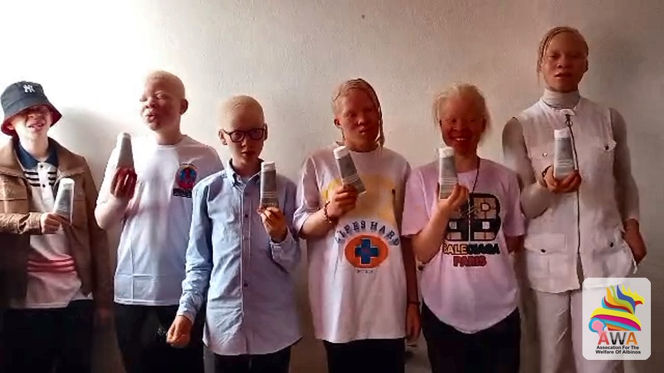 Young people with albinism holding their sunscreen bottles